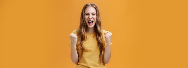 Kostenloses Foto porträt eines glücklichen, fröhlichen, glücklichen jungen europäischen mädchens mit langen, natürlichen, gewellten haaren, die geballte fi