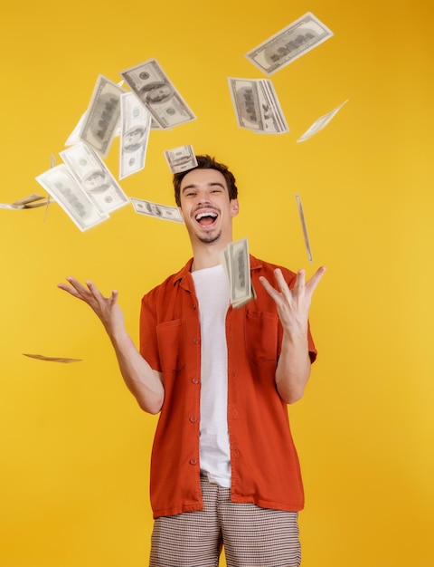 Porträt eines glücklichen jungen Mannes, der Geld hochwirft, während er auf isoliertem Hintergrund steht