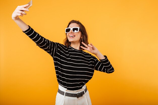 Porträt eines glücklichen Mädchens in der Sonnenbrille, die ein selfie nimmt