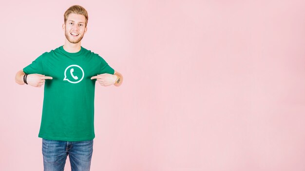 Porträt eines glücklichen Mannes, der auf sein T-Shirt mit whatsapp Ikone zeigt