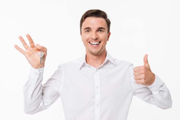 Porträt eines glücklichen Mannes im weißen Hemd, das Schlüssel hält