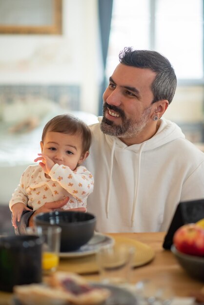 Porträt eines glücklichen Vaters, der mit seinem kleinen Sohn am Tisch sitzt