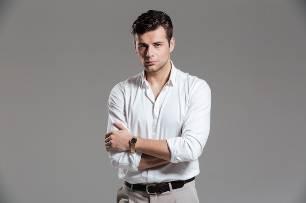Porträt eines gutaussehenden fokussierten Mannes im weißen Hemd, das aufwirft