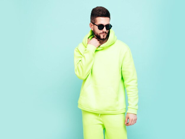 Porträt eines gutaussehenden, lächelnden Modells Sexy stilvoller Mann in gelbem Hoodie ohne Logo Kleidungs-Branding-Mockup Designvorlage für lässige Sportbekleidung Modemann isoliert auf Blau im Studio
