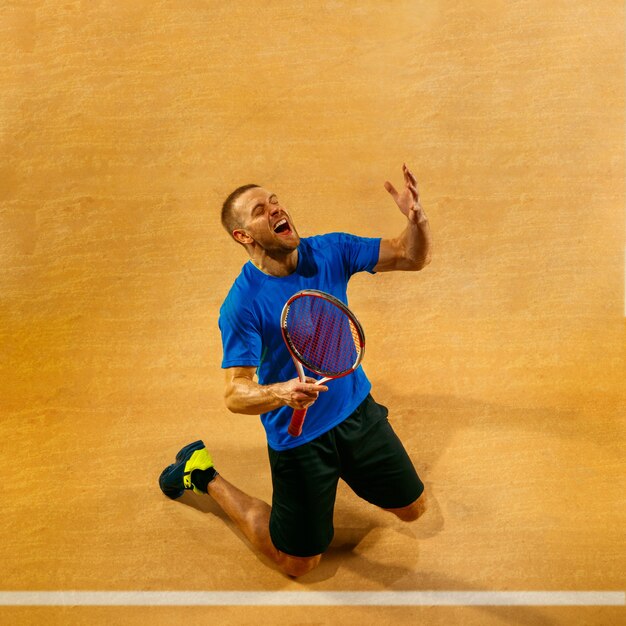 Porträt eines gutaussehenden männlichen Tennisspielers, der seinen Erfolg auf einer Hofwand feiert