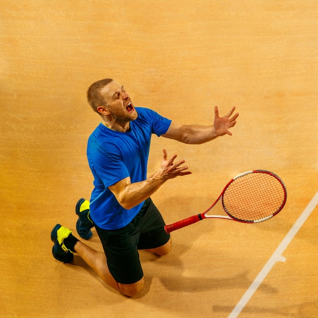 Porträt eines gutaussehenden männlichen Tennisspielers, der seinen Erfolg auf einer Hofwand feiert