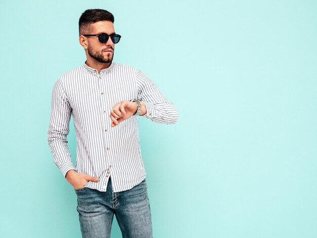 Porträt eines gutaussehenden, selbstbewussten Modells Sexy stilvoller Mann in Hemd und Jeans Mode-Hipster-Mann posiert in der Nähe der blauen Wand im Studio