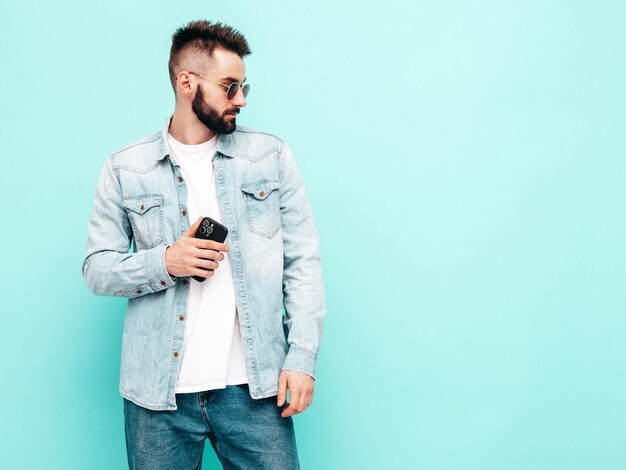 Porträt eines gutaussehenden, selbstbewussten Modells. Sexy, stilvoller Mann Mode-Hipster-Mann posiert in der Nähe einer Wand im Studio