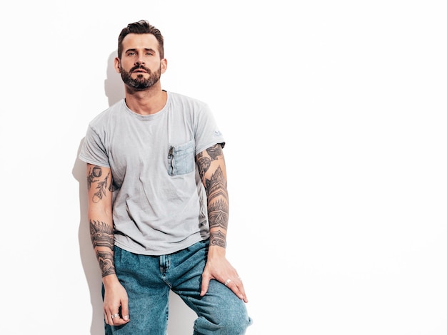 Porträt eines gutaussehenden, selbstbewussten, stilvollen Hipster-Lambersexual-Modells Sexy Mann in T-Shirt und Jeans Modemann isoliert auf weißer Wand im Studio