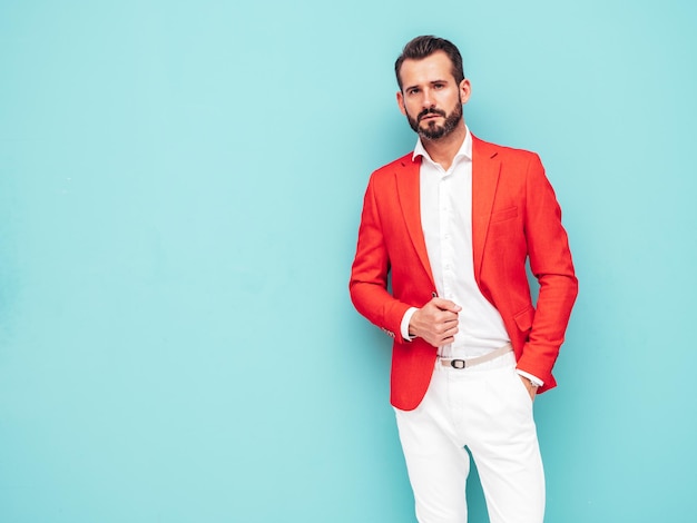 Porträt eines gutaussehenden, selbstbewussten, stilvollen Hipster-Lambersexual-Modells Sexy moderner Mann in elegantem rotem Anzug Modemann posiert im Studio in der Nähe der blauen Wand