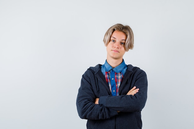 Kostenloses Foto porträt eines gutaussehenden teenagers, der die arme in hemd, hoodie verschränkt hält und selbstbewusste vorderansicht sieht