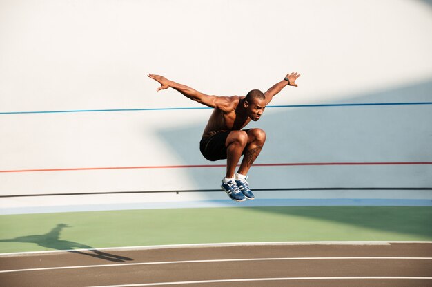 Porträt eines halbnackten stark sitzenden afrikanischen Sportlers, der springt