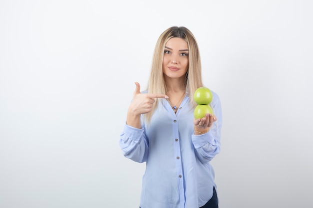 Porträt eines hübschen Frauenmodells, das auf frische Äpfel zeigt.