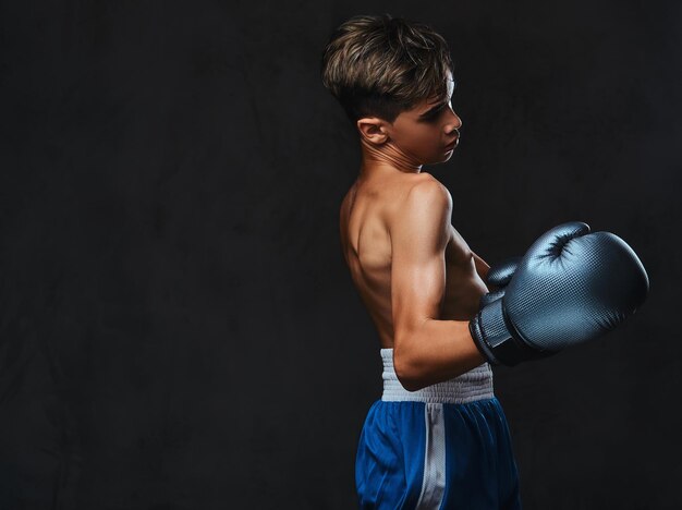 Porträt eines hübschen jungen Boxers ohne Hemd während Boxübungen, konzentriert auf den Prozess mit ernster, konzentrierter Gesichtsbehandlung.