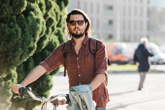 Kostenloses Foto porträt eines hübschen jungen mannes, der mit fahrrad auf der straße geht