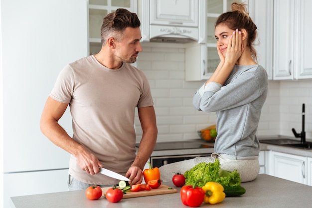 Porträt eines hübschen liebevollen Paares, das zusammen Salat kocht