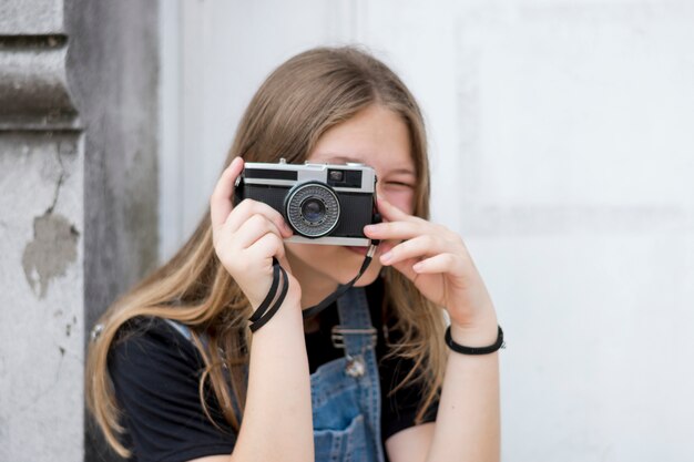 Porträt eines jugendlichen weiblichen Fotografen, der ihr Gesicht mit der Kamera bedeckt
