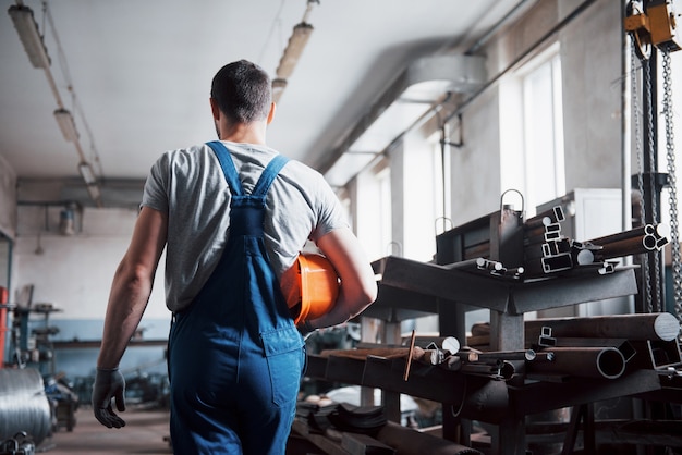 Porträt eines jungen Arbeiters in einem Schutzhelm in einer großen Abfallrecyclingfabrik.