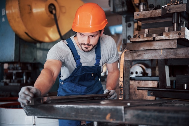 Porträt eines jungen Arbeiters in einem Schutzhelm in einer großen Abfallrecyclingfabrik.