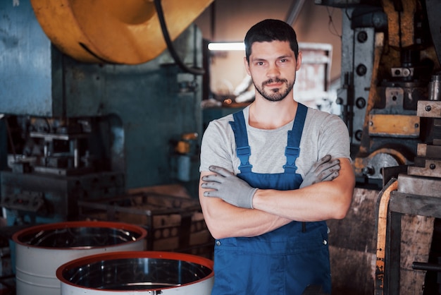 Porträt eines jungen Arbeiters in einem Schutzhelm in einer großen Abfallrecyclingfabrik.