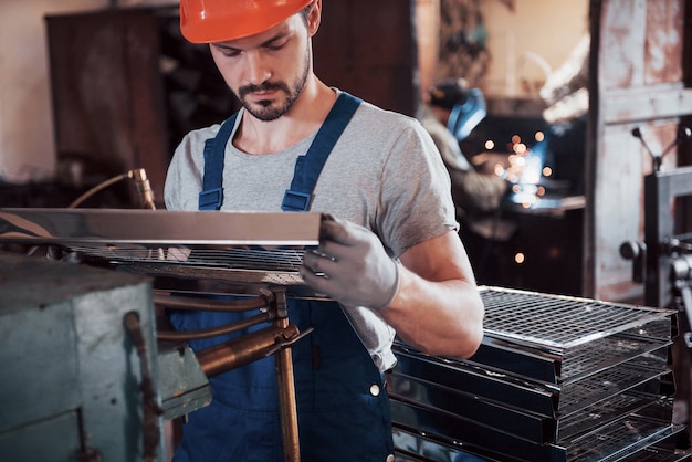 Porträt eines jungen Arbeiters in einem Schutzhelm in einer großen Abfallrecyclingfabrik.