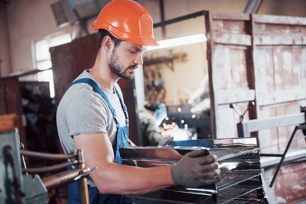 Porträt eines jungen Arbeiters in einem Schutzhelm in einer großen Abfallrecyclingfabrik.