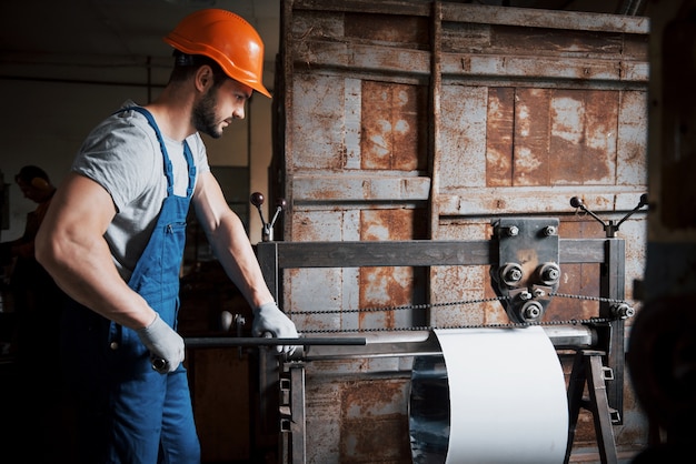 Porträt eines jungen Arbeiters in einem Schutzhelm in einer großen Metallbearbeitungsanlage.