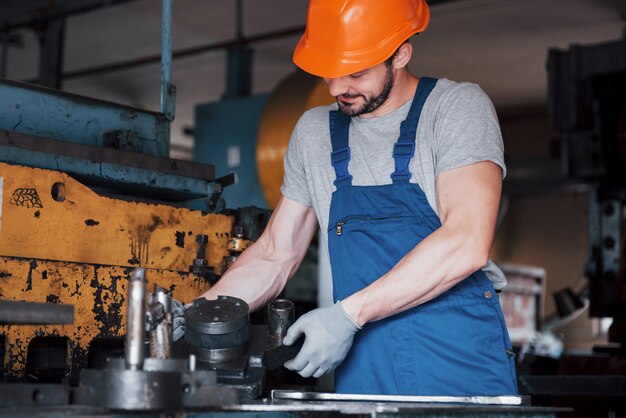 Porträt eines jungen Arbeiters in einem Schutzhelm in einer großen Metallbearbeitungsanlage.