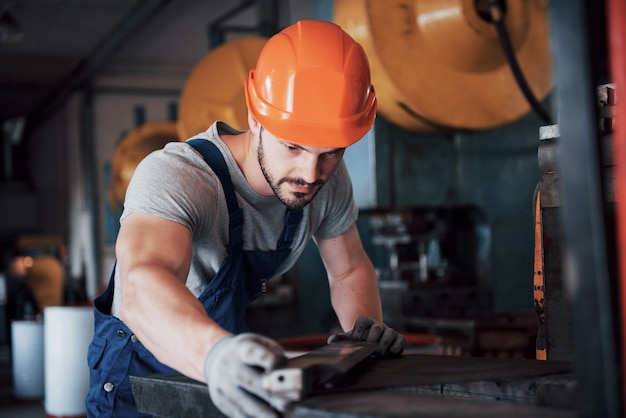 Porträt eines jungen Arbeiters in einem Schutzhelm in einer großen Metallbearbeitungsanlage.