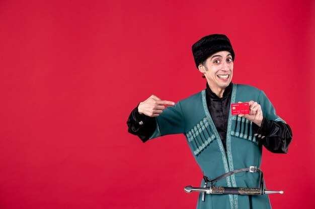 Porträt eines jungen aserbaidschanischen Mannes in traditioneller Tracht mit Kreditkarte auf Rot