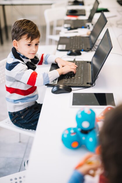 Porträt eines Jungen, der den Laptop betrachtet das Kind spielt mit Spielzeug in der Klasse verwendet