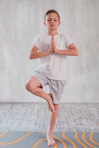 Porträt eines Jungen, der in der Yogahaltung auf einem Bein steht