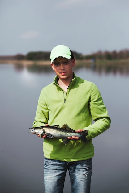 Porträt eines jungen fischers, der frische gefangene fische hält