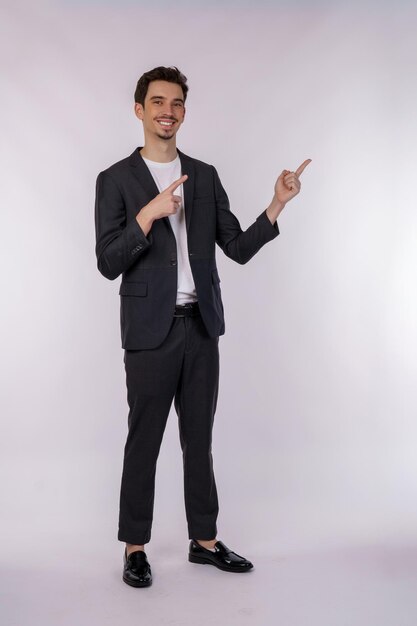 Porträt eines jungen Geschäftsmannes, der mit dem Finger auf den Kopierraum zeigt, der auf weißem Studiohintergrund isoliert ist