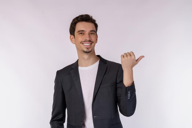 Porträt eines jungen Geschäftsmannes, der mit dem Finger auf den Kopierraum zeigt, der auf weißem Studiohintergrund isoliert ist