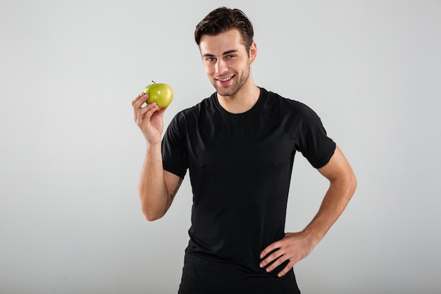 Porträt eines jungen gesunden Mannes, der grünen Apfel hält