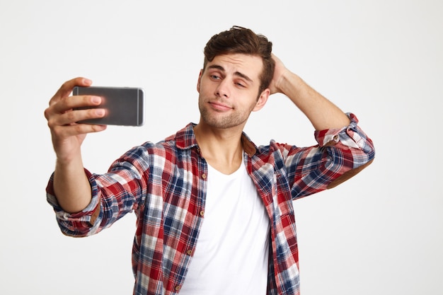 Porträt eines jungen gutaussehenden mannes, der ein selfie nimmt