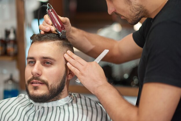 Porträt eines jungen gutaussehenden Mannes, der genießt, einen neuen Haarschnitt im Friseursalon zu erhalten.