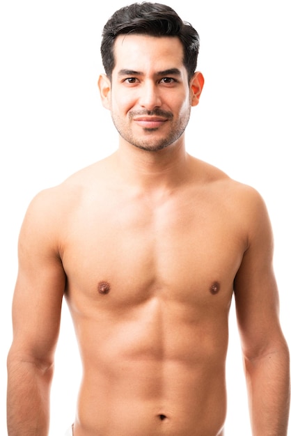 Porträt eines jungen hispanischen Mannes in den 20er Jahren mit muskulösem Körper, der ohne Hemd steht