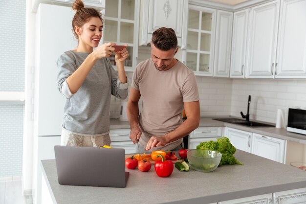 Porträt eines jungen liebevollen Paares, das zusammen Salat kocht