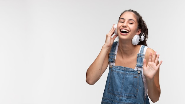 Porträt eines jungen Mädchens in Overalls, das Musik über Kopfhörer hört