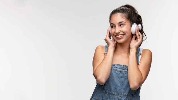 Porträt eines jungen Mädchens in Overalls, das Musik über Kopfhörer hört