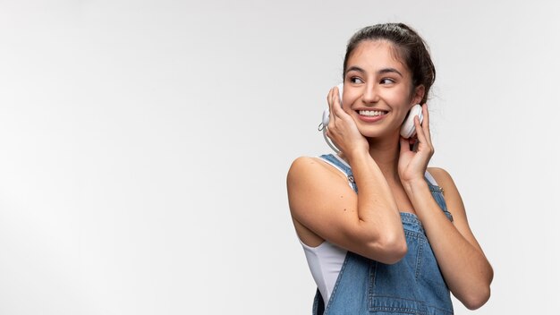 Porträt eines jungen Mädchens in Overalls, das Musik über Kopfhörer hört