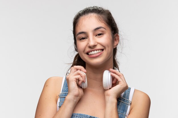 Porträt eines jungen Mädchens in Overalls, das Musik über Kopfhörer hört