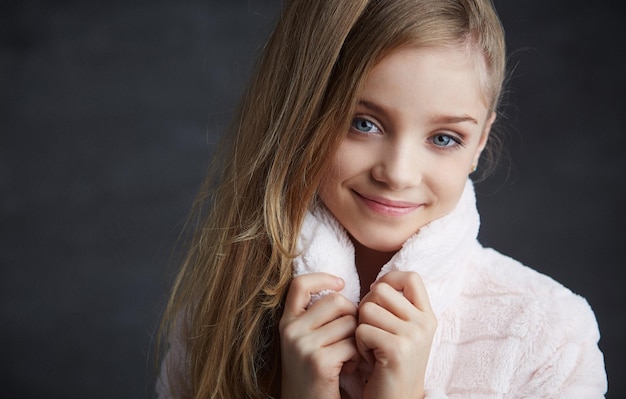 Porträt eines jungen Mädchens mit blauen Augen im weißen Mantel.