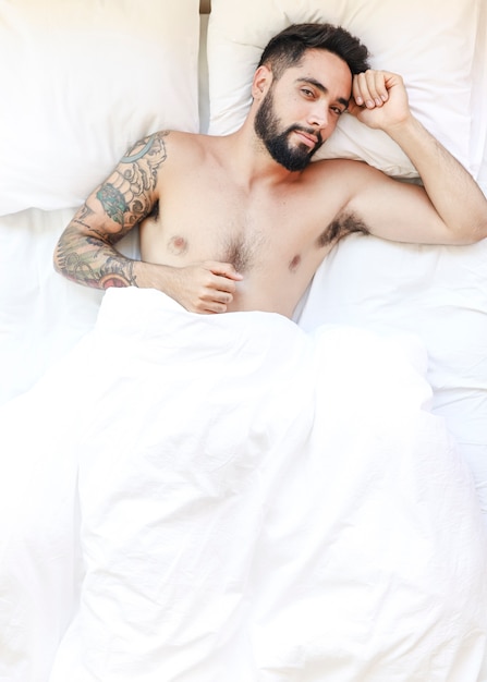 Porträt eines jungen Mannes, der auf Bett liegt