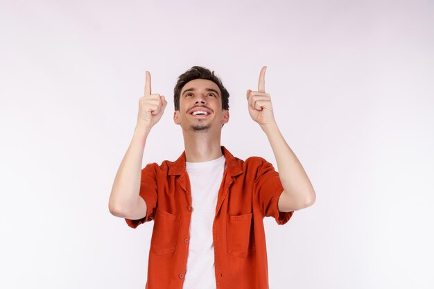 Porträt eines jungen Mannes, der mit dem Finger auf den Kopierraum zeigt, der auf weißem Studiohintergrund isoliert ist