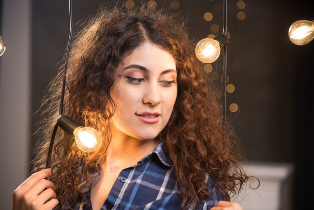 Porträt eines jungen Models im karierten Hemd, das in der Nähe von Lampen posiert