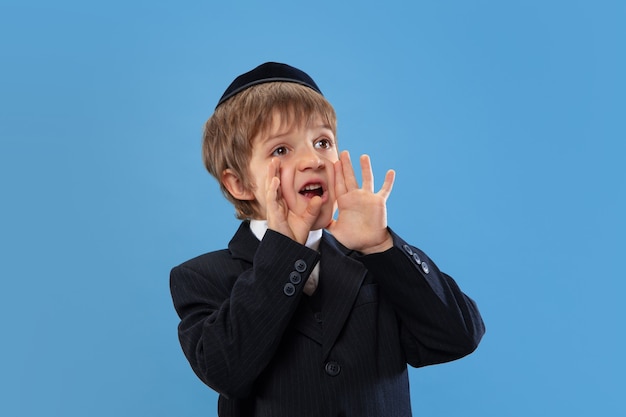 Porträt eines jungen orthodoxen jüdischen Jungen isoliert auf blauem Studio