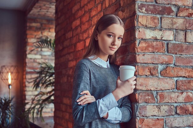 Porträt eines jungen, schlanken, sinnlichen Mädchens in einem grauen Kleid, das ag lehnt